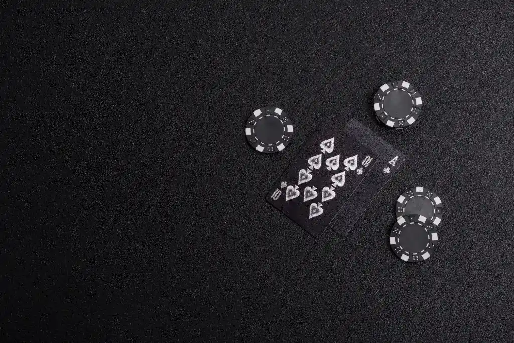 ista superior de cartas de baralho e fichas de poker pretas em um fundo elegante para ilustrar as vantagens de um cassino com cashback.