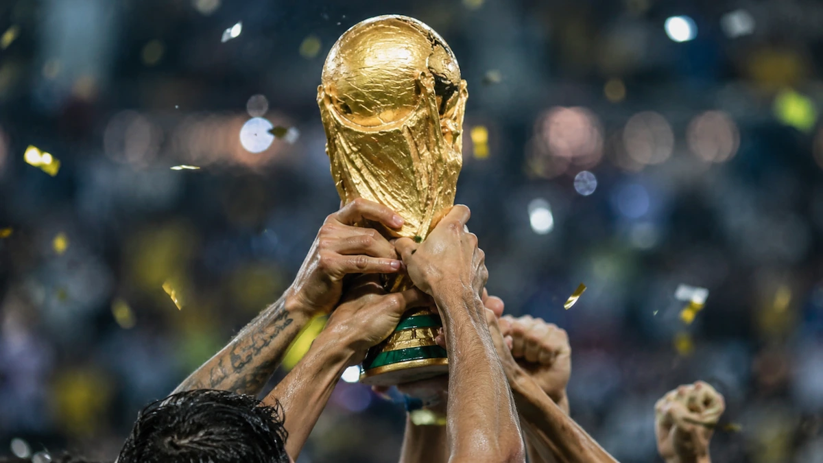 Taça dourada erguida por jogadores em comemoração para representar quem vai ganhar a Copa do Mundo 2026.