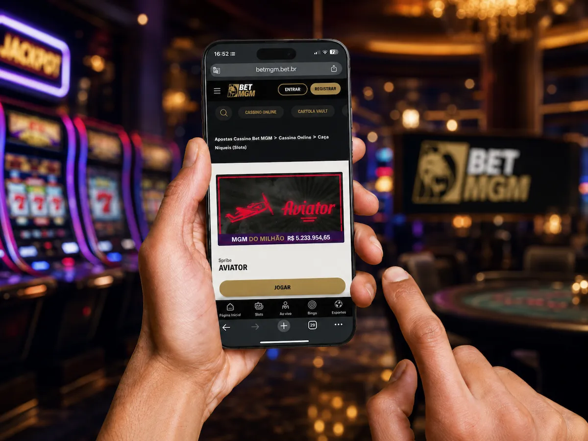 Pessoa segurando um celular que exibe o jogo Aviator no site BetMGM, em um cenário de cassino ao fundo. Excelente oportunidade para usar seus 5 reais grátis para apostar slots e crash games.